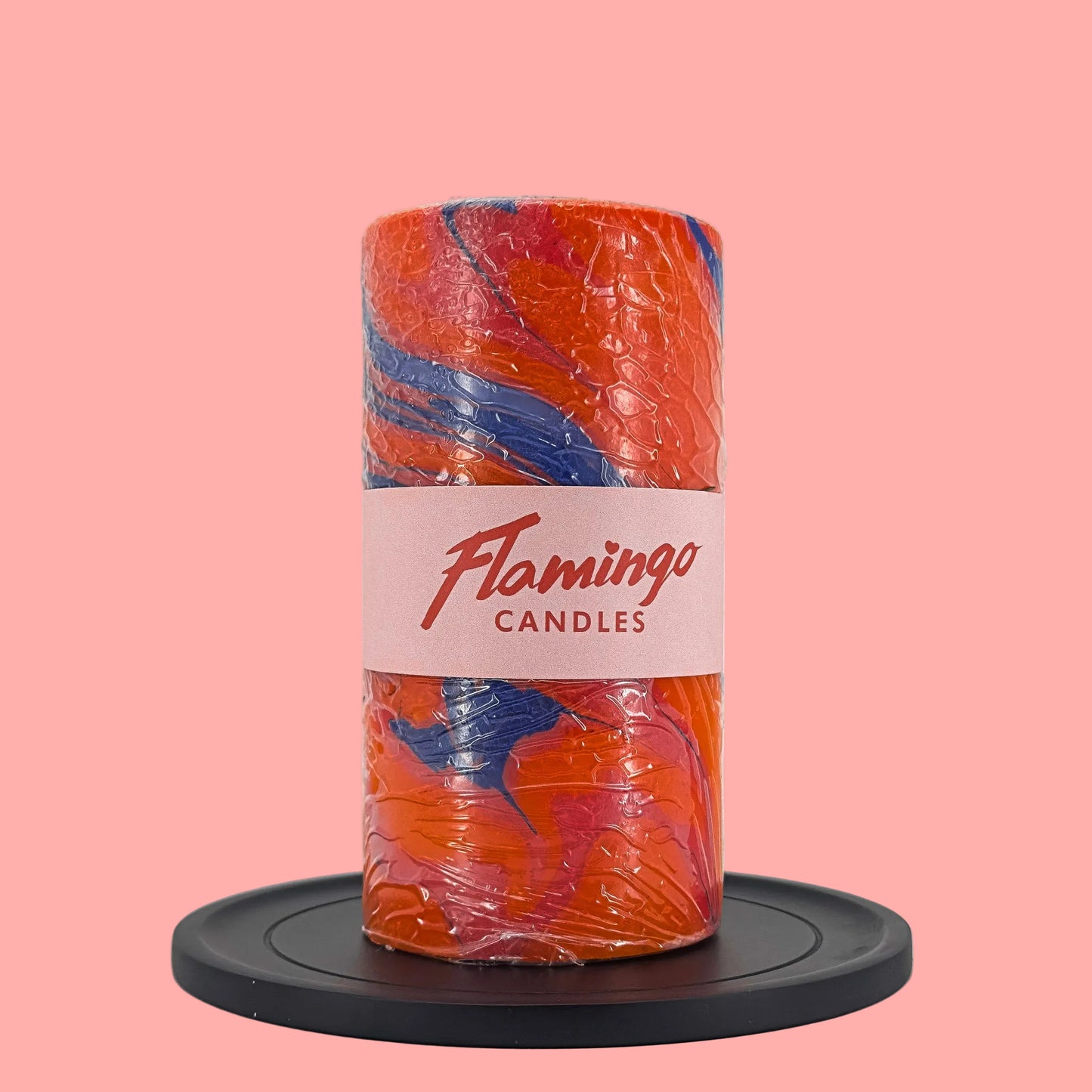 Cylindrical candle with orange and blue marbled design on a white background, featuring 'Flamingo Candles' branding.