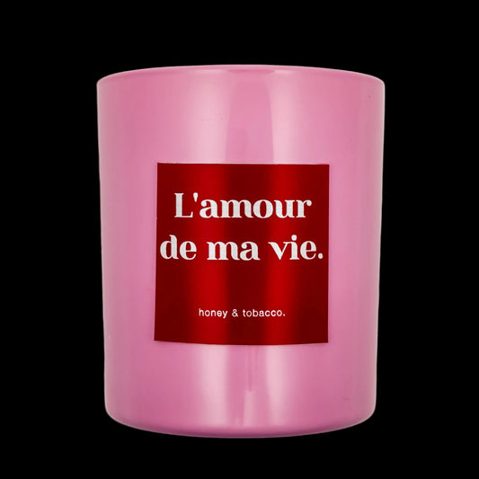 Pink candle with a red label displaying 'L'amour de ma vie' on a black background