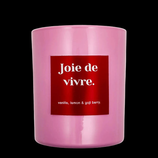 Pink candle with a red label displaying 'Joie de vivre' on a black background