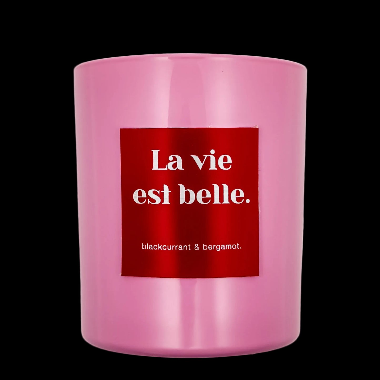 Pink candle with a red label displaying 'La vie est belle' on a black background
