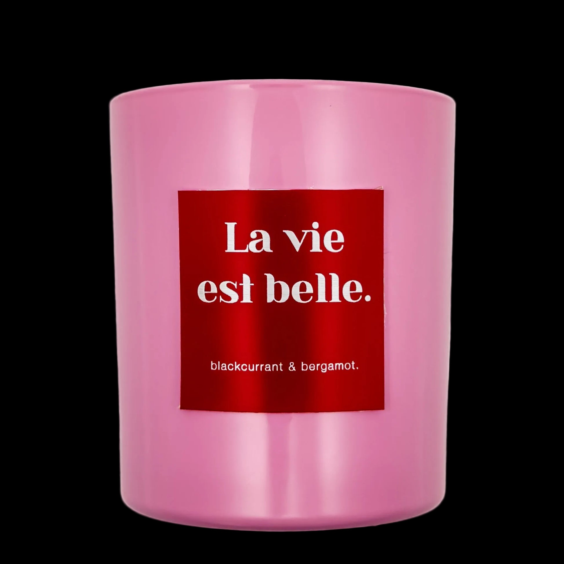 Pink candle with a red label displaying 'La vie est belle' on a black background